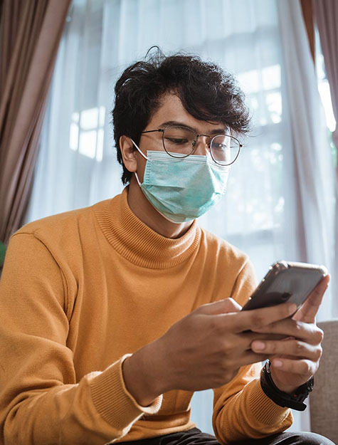 Image of man using smartphone with facemask